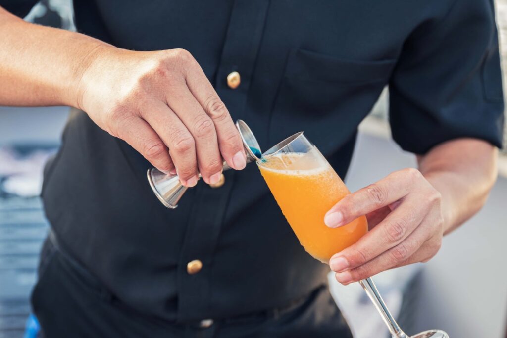 barista prepara un cocktail con un jigger